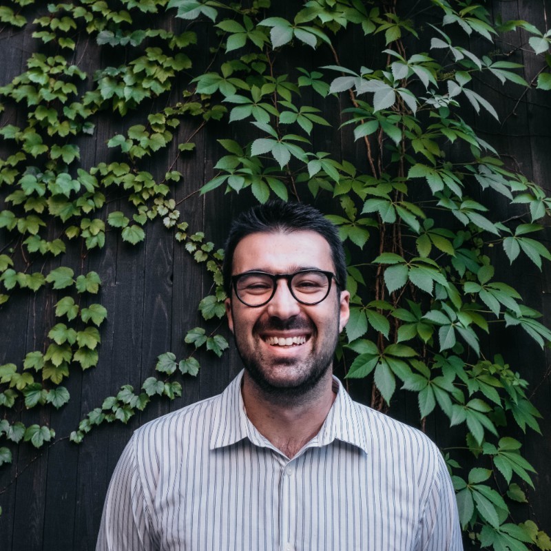 a man smiling in front of a wall of ivy