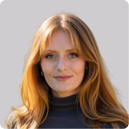 Portrait of a smiling woman with long red hair and blue eyes wearing a black turtleneck.