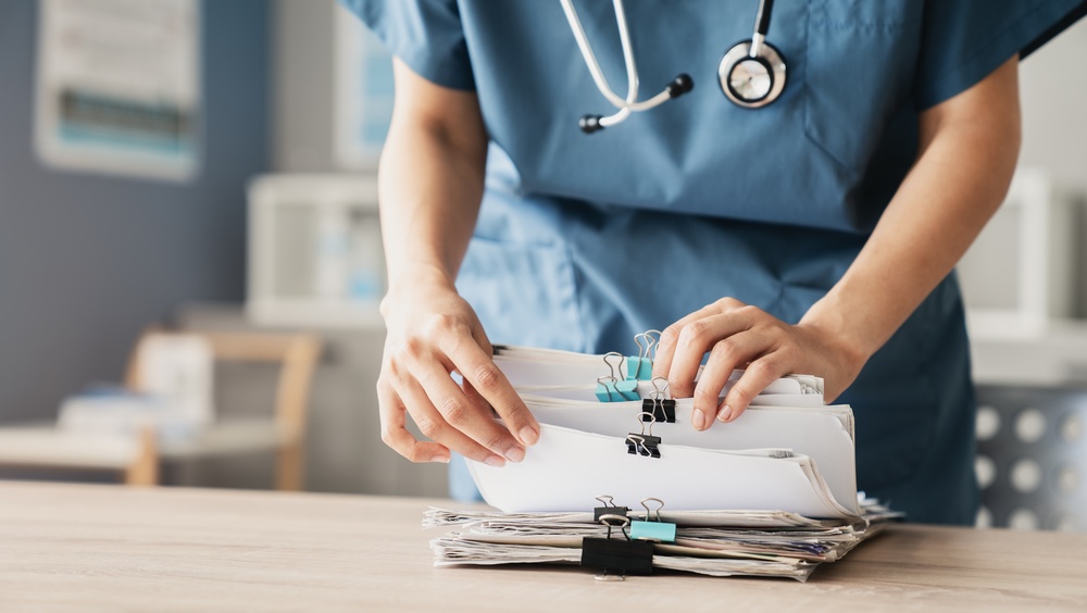 Nurse sorting through stacks of paper forms