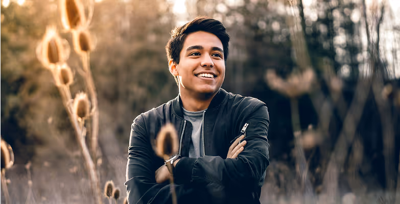 Smiling person outdoors in a field, exuding confidence and positivity, reflecting HR DataHub's innovative spirit.