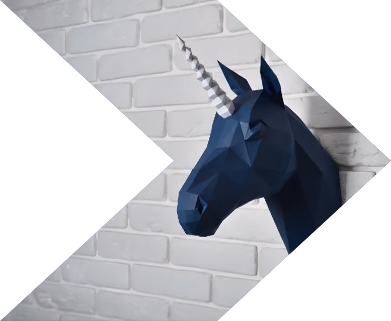 Geometric dark blue unicorn head sculpture mounted on a white brick wall.