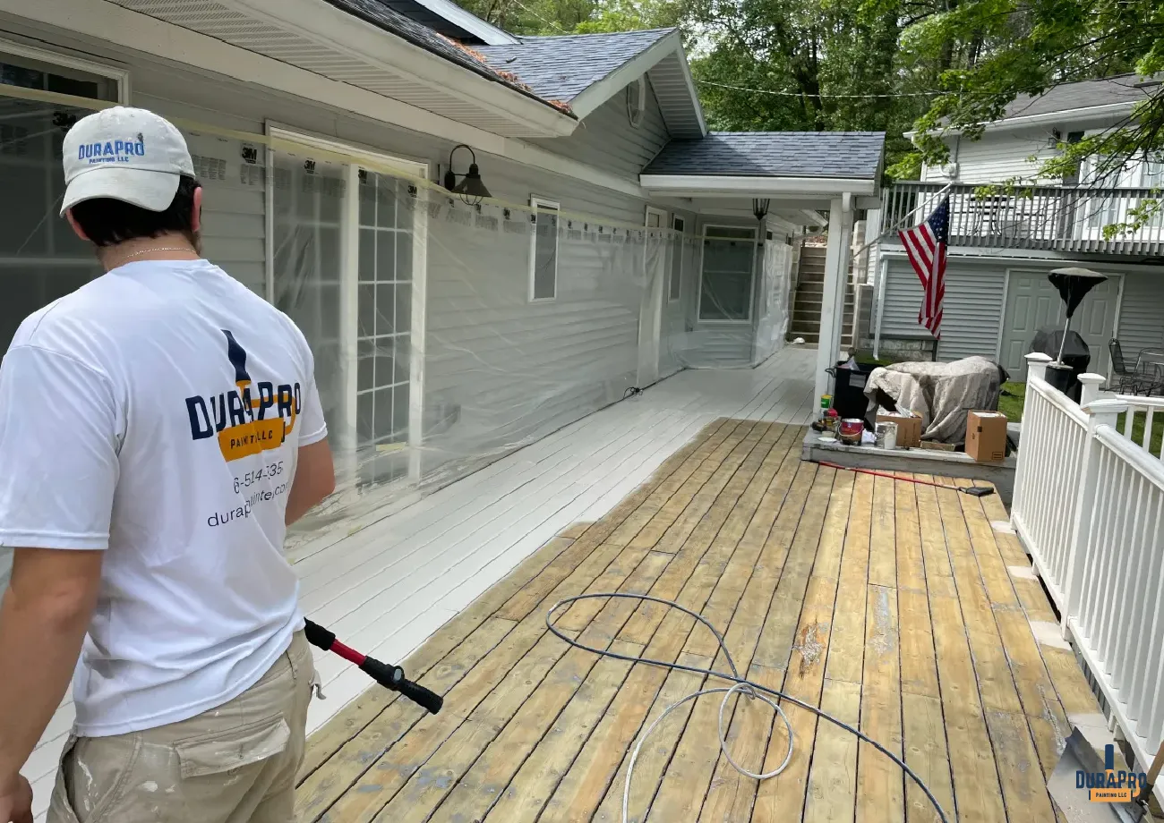 DuraPro painting employee in DuraPro shirt working on staining a deck at a lakefront home in Michigan