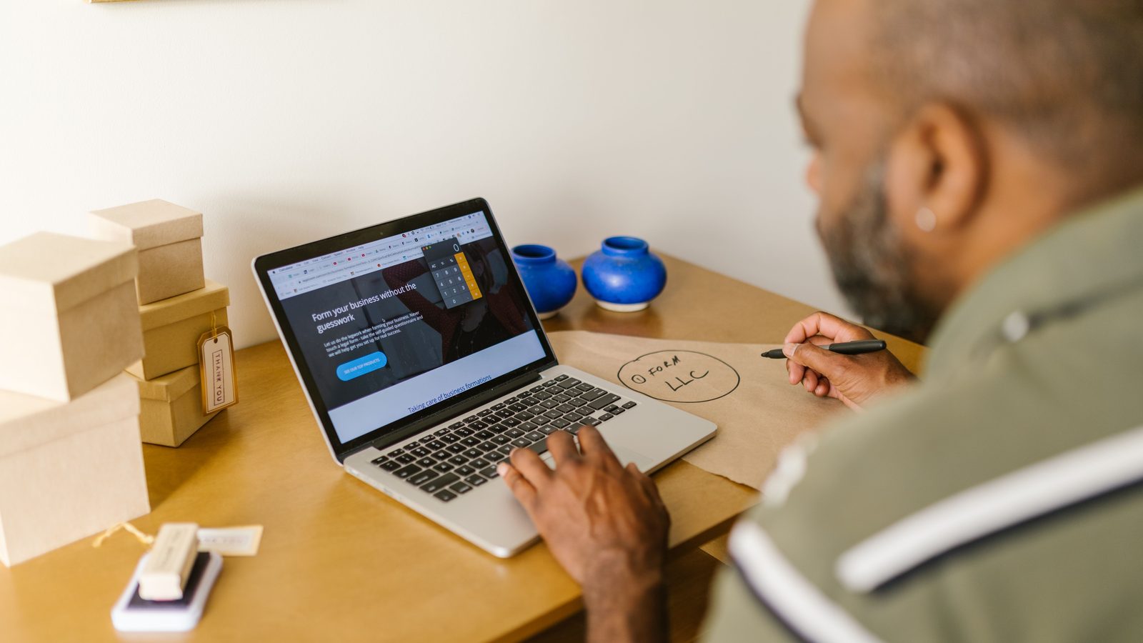 Small business owner reviewing sales data on a laptop beside packed shipping boxes