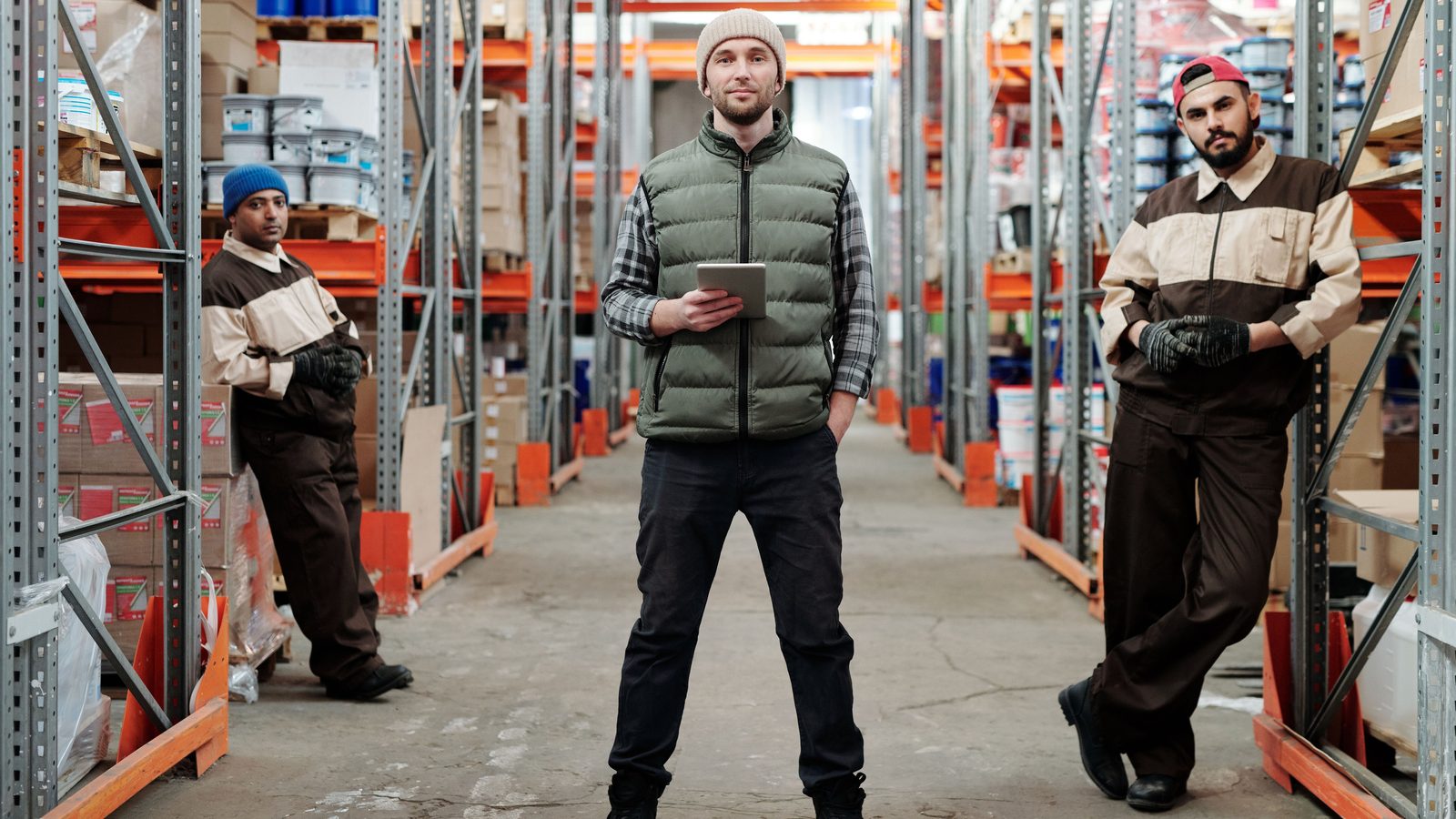 Warehouse team checking stock on tall storage racks with a tablet
