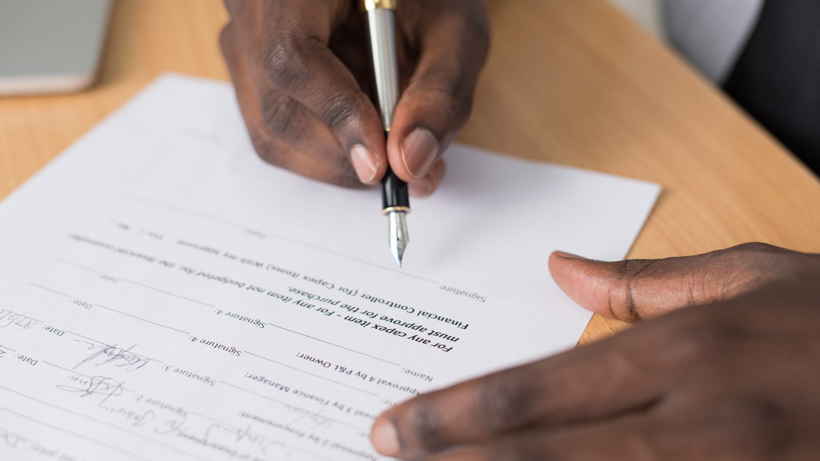 Hands signing contract pen desk.