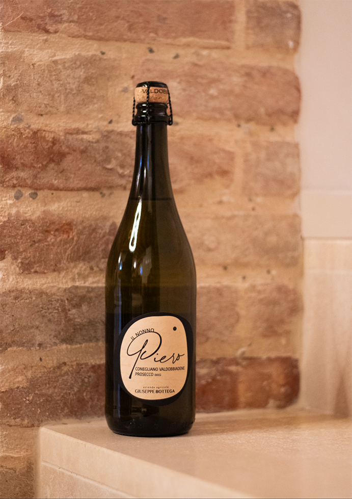 Bottiglia di Prosecco DOCG “Il Nonno Piero” Conegliano Valdobbiadene, Prosecco Frizzante italiano di qualità con etichetta artigianale su vetro scuro.