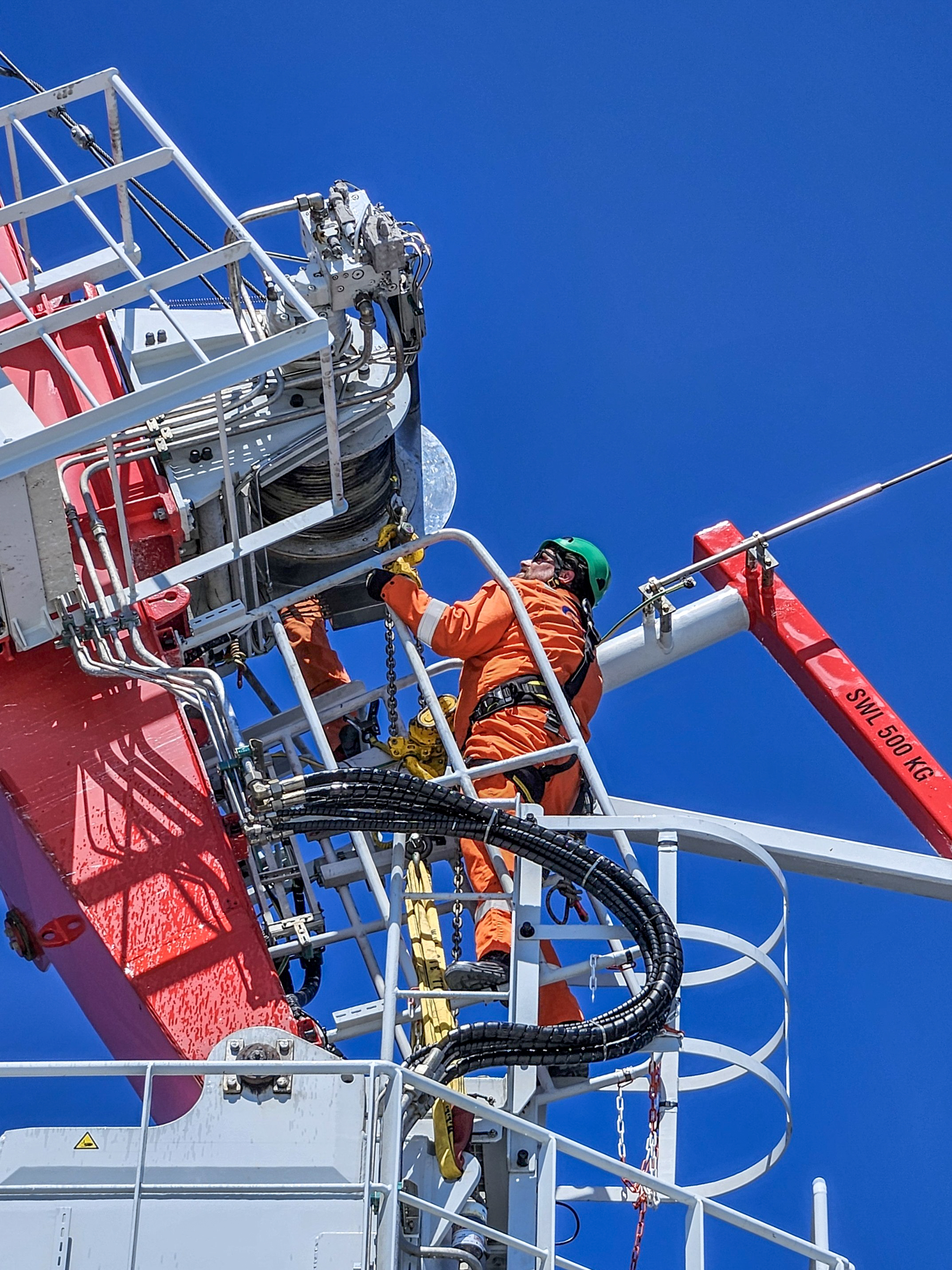 Conbit technician performing inspection and maintenance on offshore platform crane