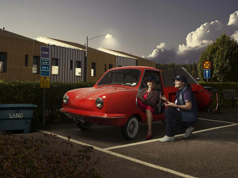 Conceptual image of a red vintage car and two people talking at dusk
