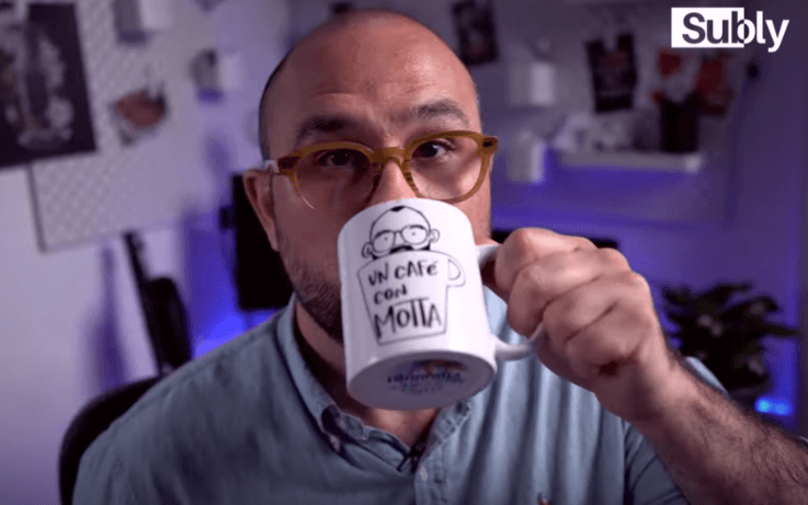 man drinking coffee from mug with un cafe con motta written on it