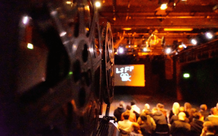 camera screening a film people in background