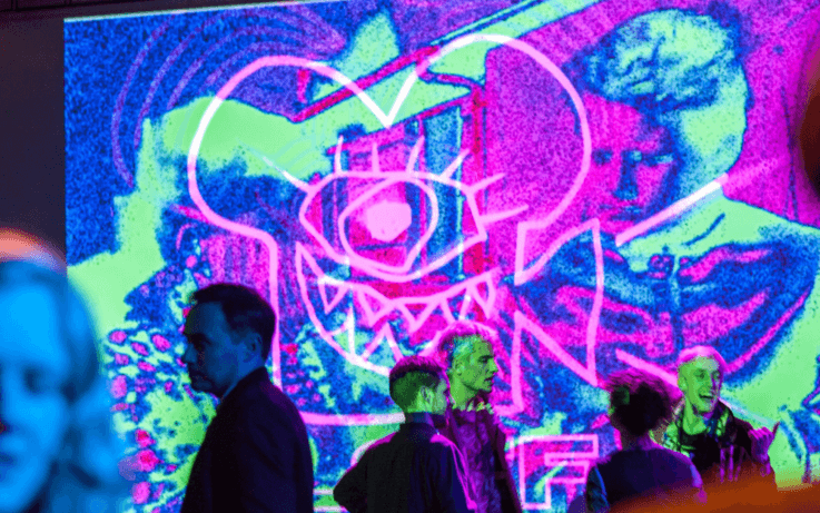 Colourful projection on wall people walking in background