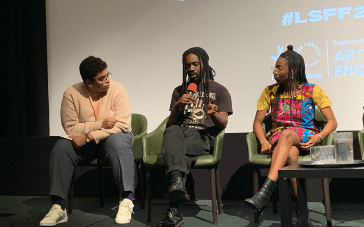 three people sitting on chairs on a panel talking