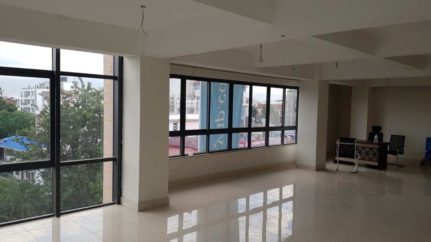 The vacant third floor at OneSky in daylight — glossy white tile, corner glazing and a ribbon window to the street