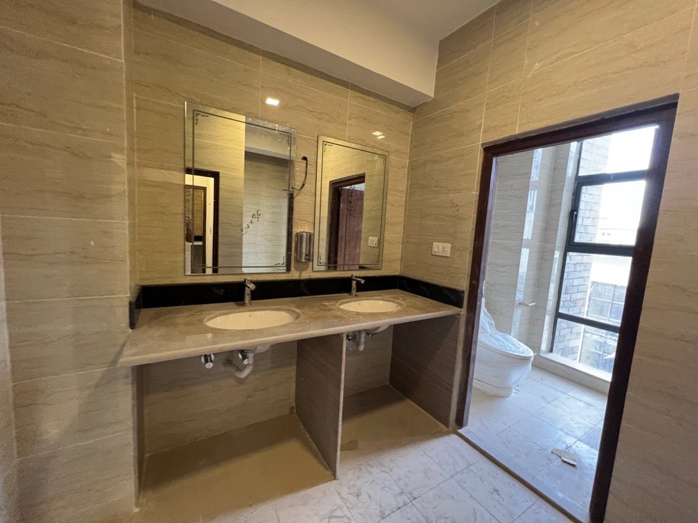 Washroom with stone counter, twin basins and full-height tiling