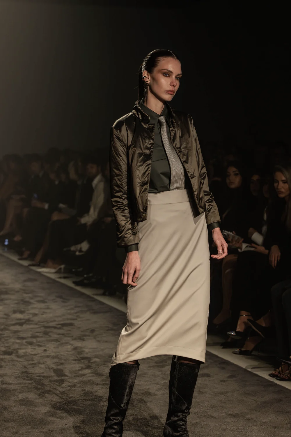 Model wearing a khaki bomber jacket, silk skirt, and tie on the runway at Farage Australia’s Summer 26 presentation, AFW 2025.
