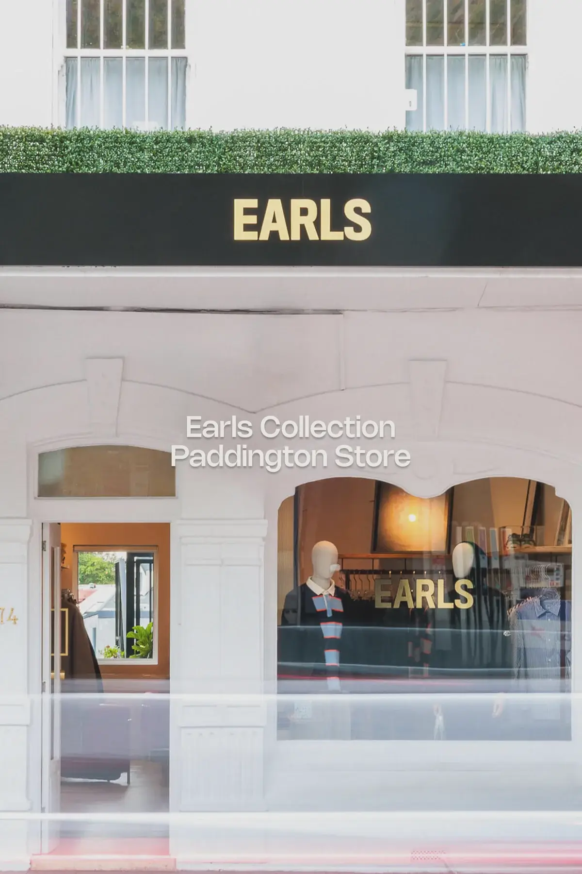 Interior of the newly opened Earls Collection Sydney store in Paddington, showcasing a clean retail space with minimalist wooden and chrome fixtures, folded knitwear, hanging garments, and a vibrant red Le Corbusier-style armchair. Natural light fills the room through a large window, highlighting the curated, contemporary menswear display.