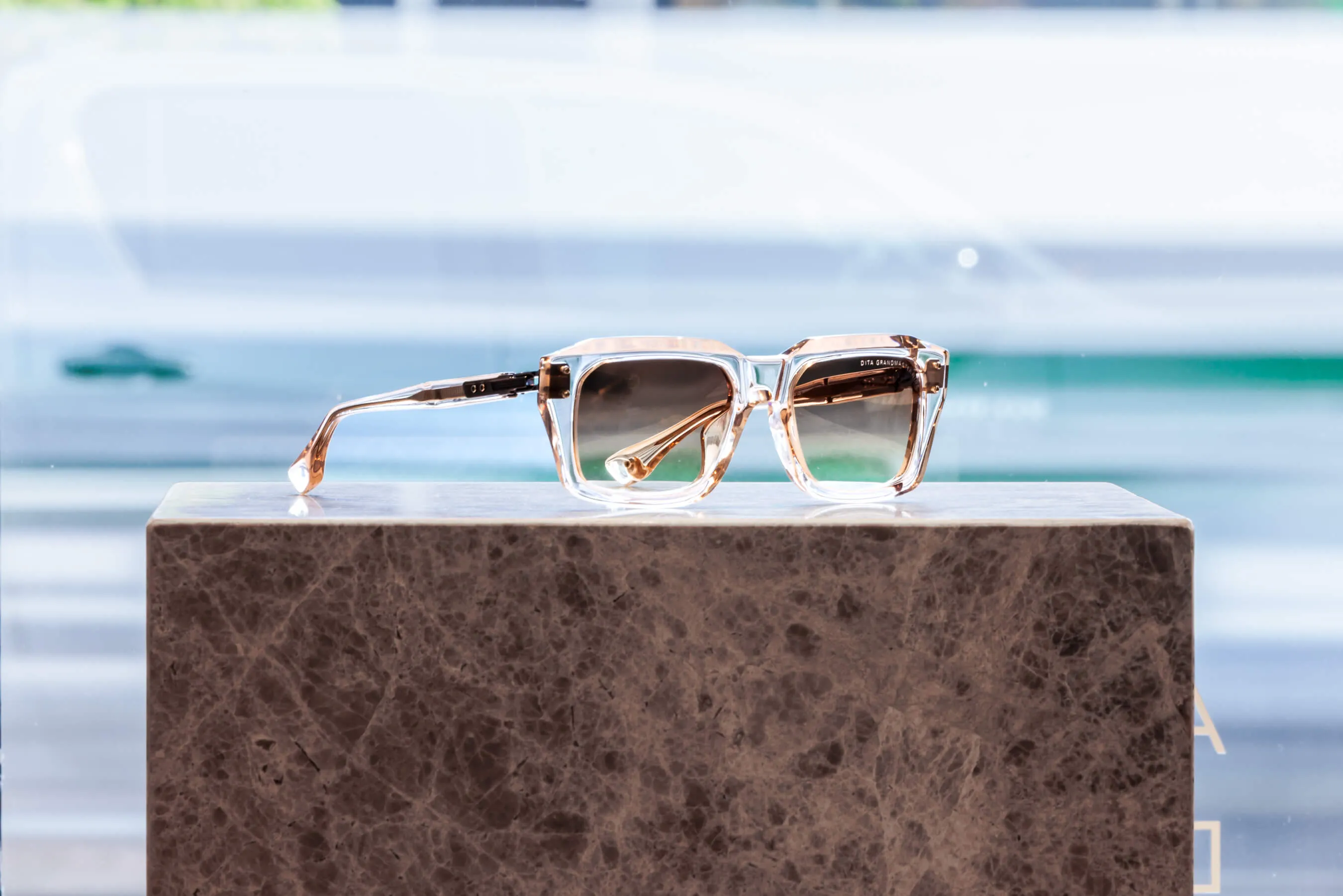 Light-toned square sunglasses on marble display block at Essu Mosman | EDG Studios