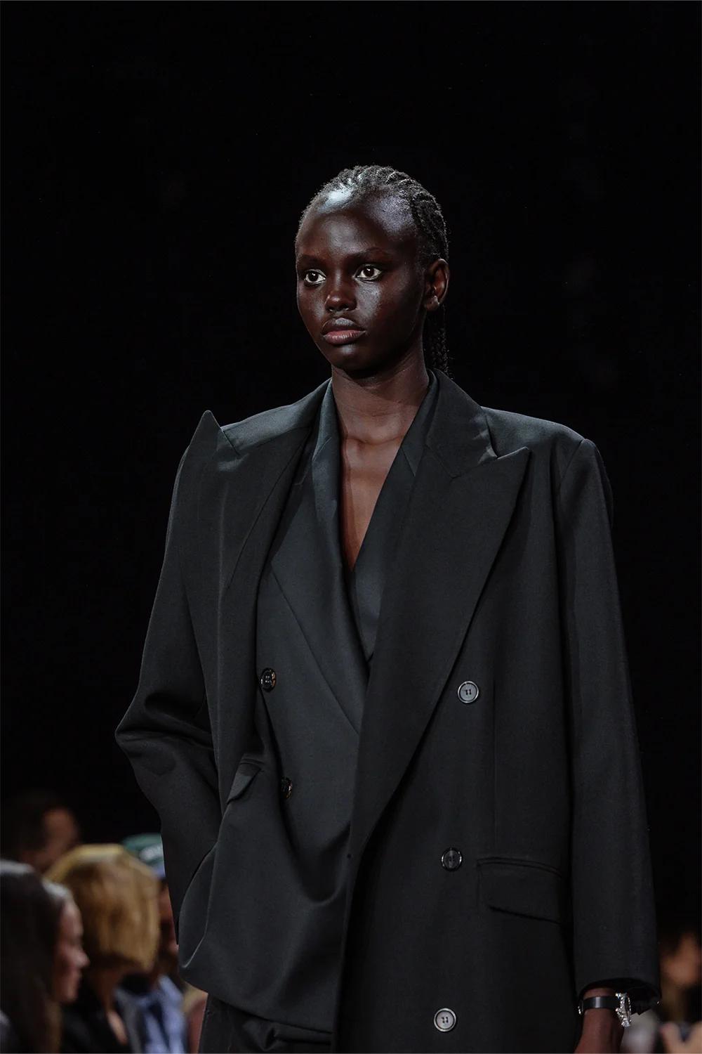 Close-up of model wearing a sharply tailored double-breasted coat in dark charcoal at Beare Park’s AFW 2025 runway show.
