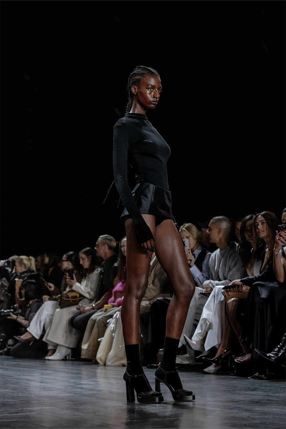 Runway model in an all-black long sleeve fitted top paired with black satin shorts during Beare Park’s show at Australian Fashion Week 2025.