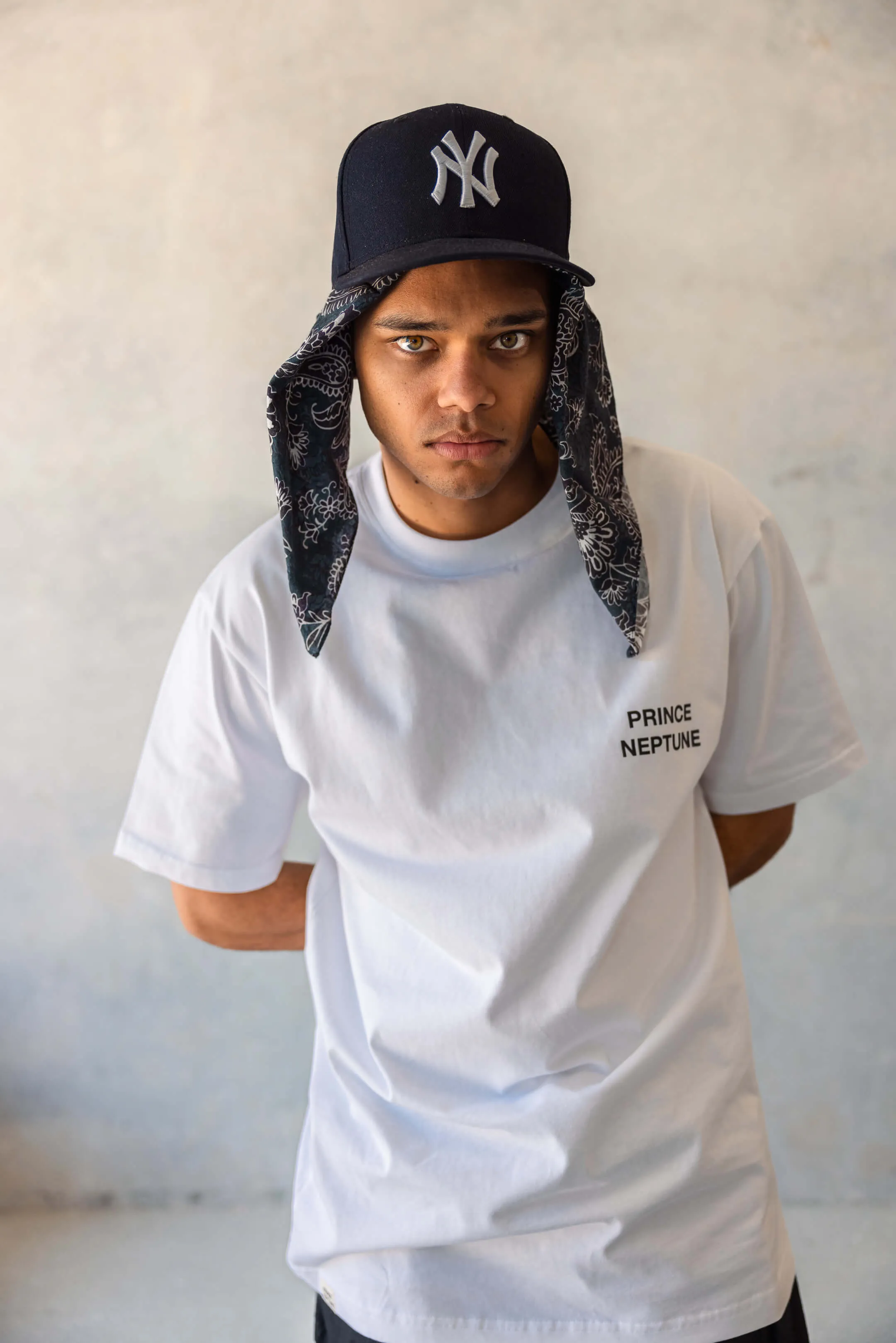 Portrait of model in Prince Neptune tee with New York Yankees cap and black bandana tucked underneath | EDG Studios
