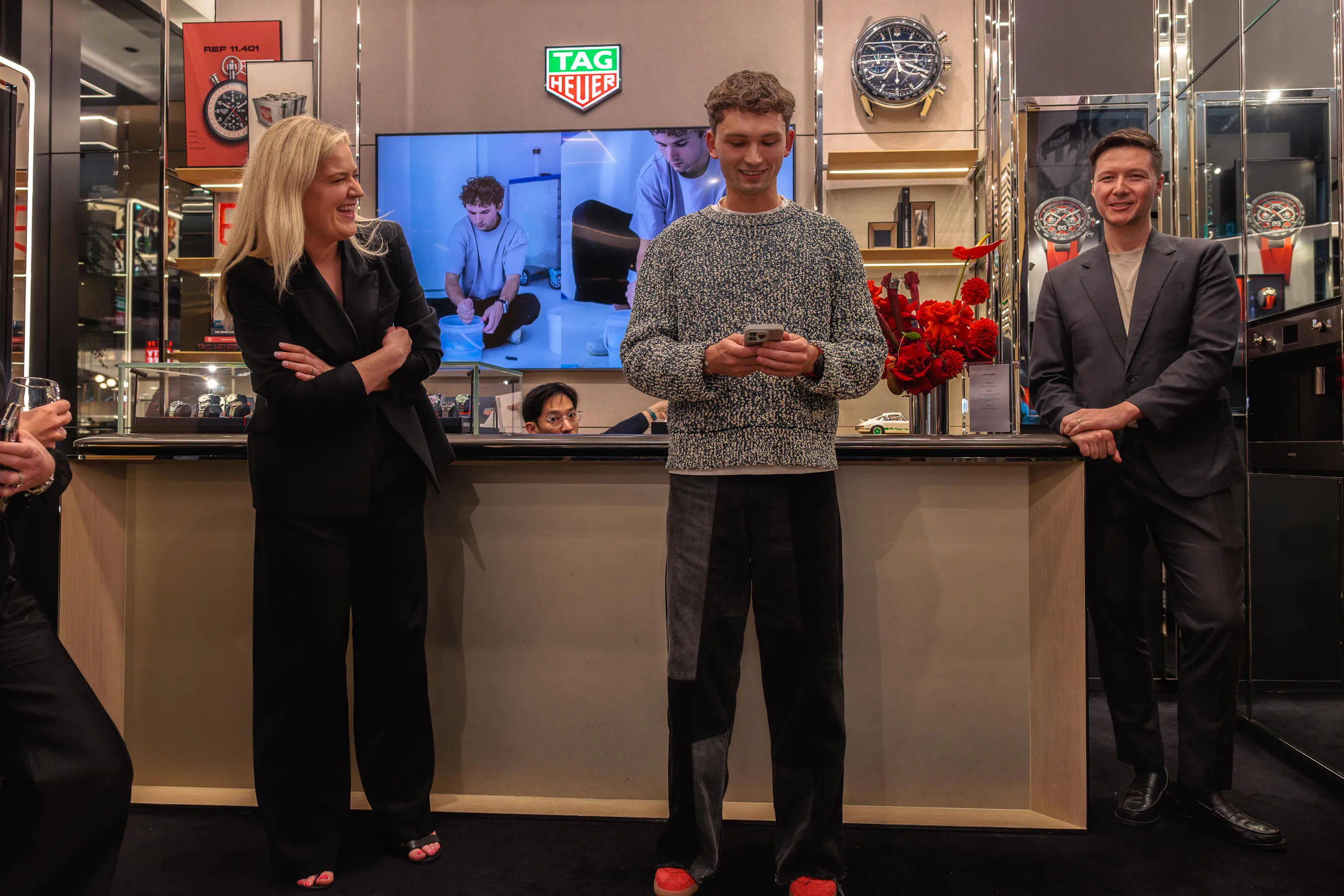 Werner Bronkhorst gives a speech at the event, flanked by two smiling guests, while a behind-the-scenes video of his creative process plays on the screen behind him | EDG Studios