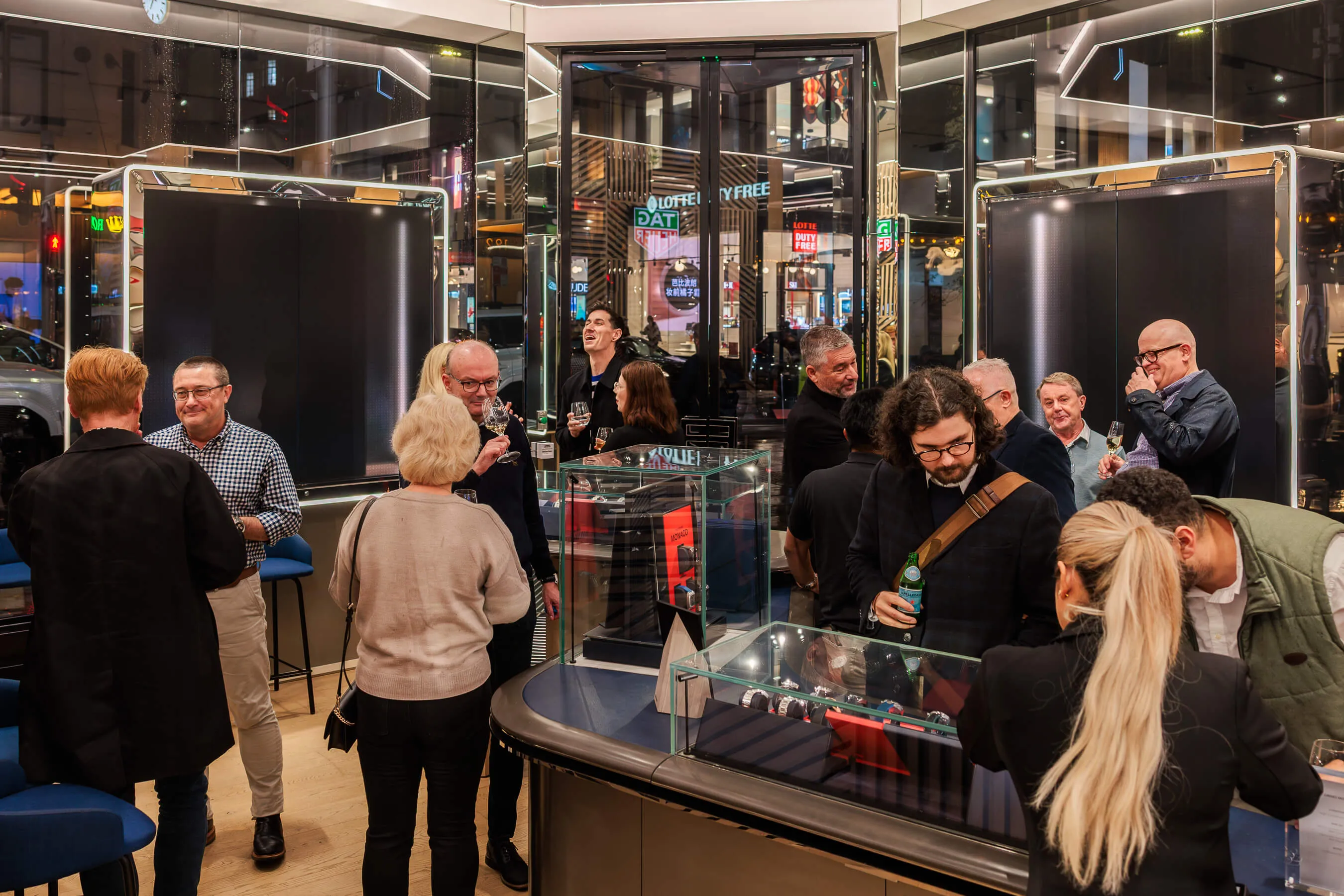 A wide shot of the event crowd inside the brightly lit Tag Heuer Sydney store, showing guests mingling around glass watch counters | EDG Studios