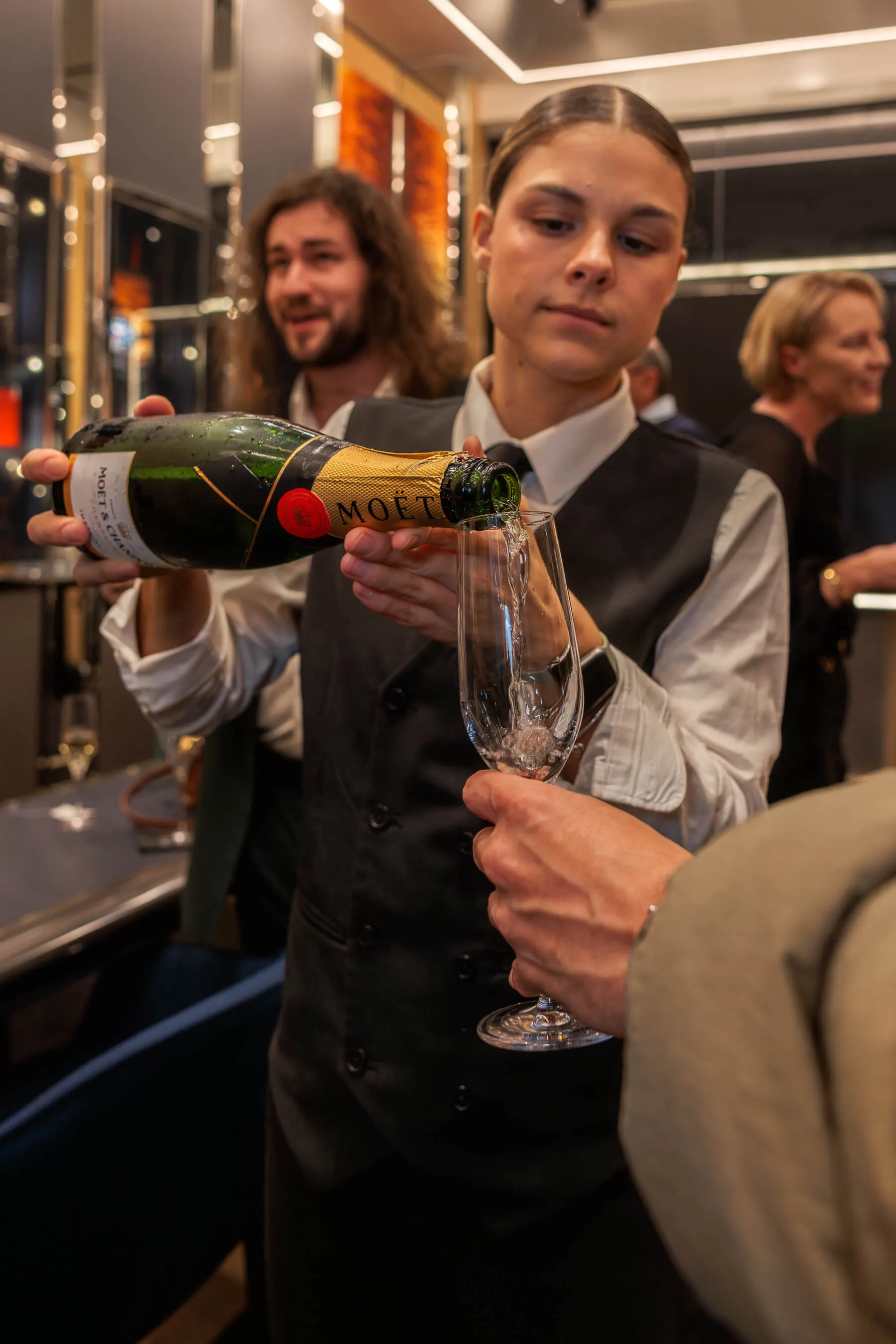 A staff member pours Moët & Chandon champagne into a flute glass for a guest, capturing the luxury atmosphere of the launch event | EDG Studios