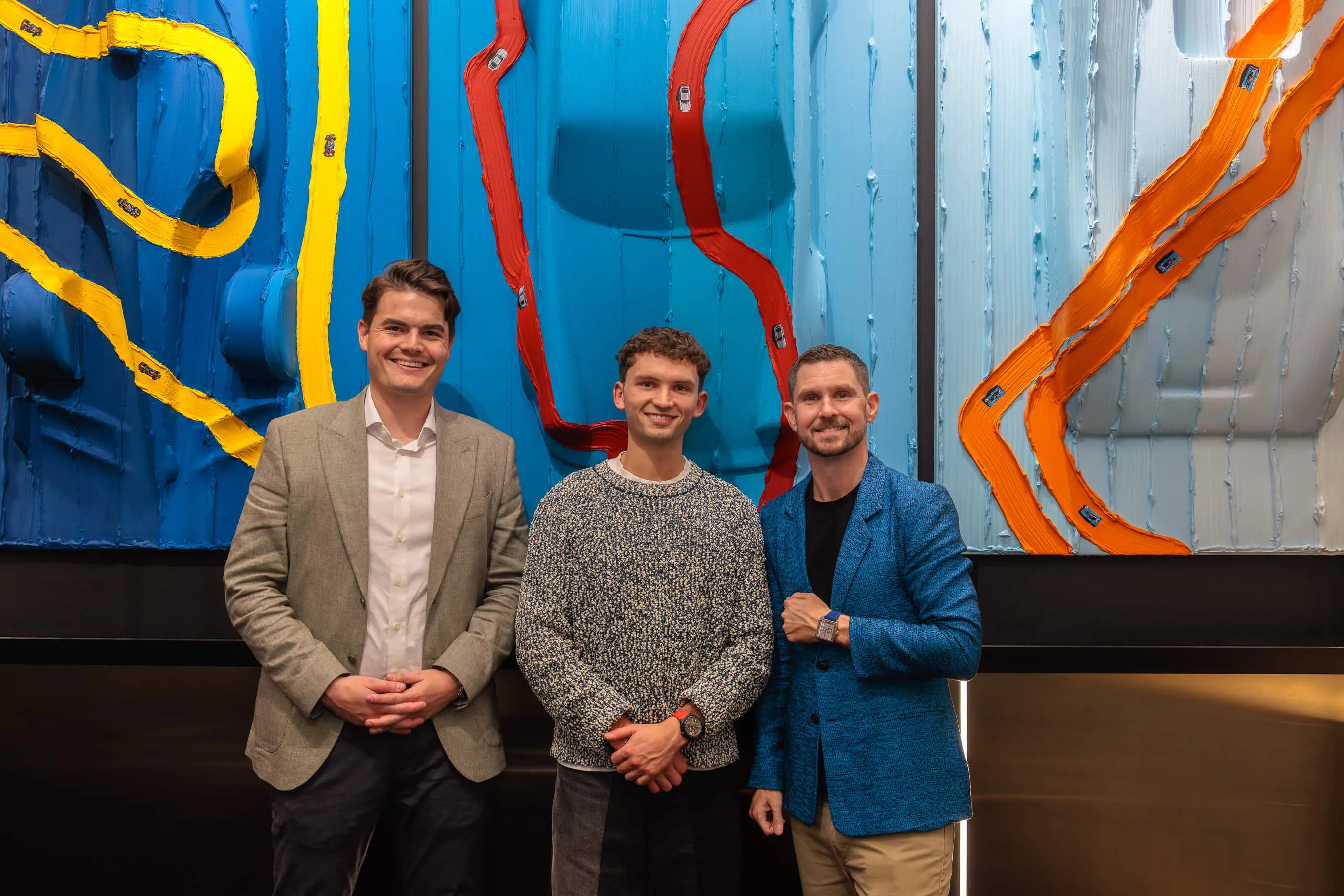 Three men stand in front of the artwork: Werner Bronkhorst (center), flanked by two guests in blazers, posing at the Tag Heuer Sydney launch | EDG Studios
