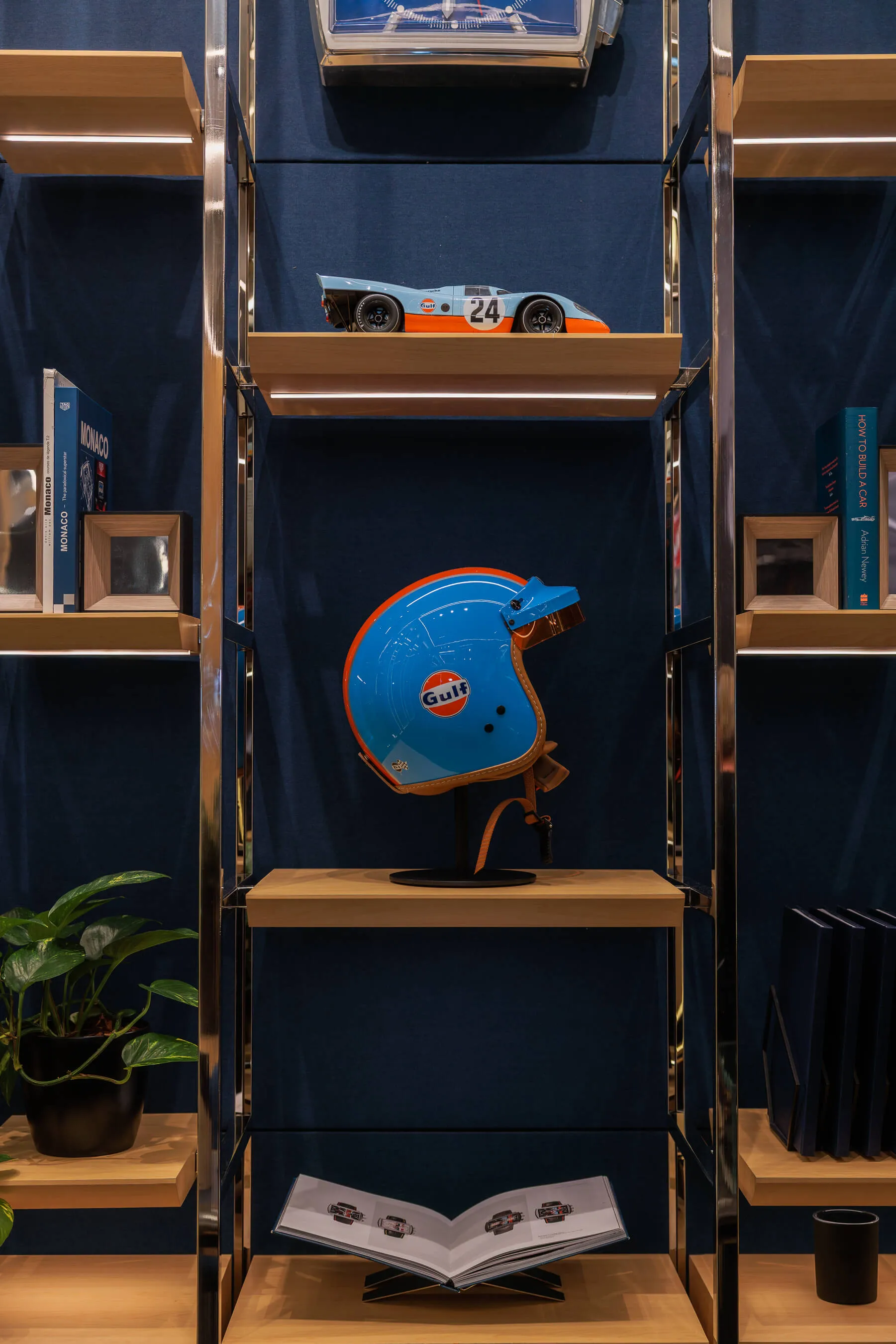 A close-up of the store display shelf featuring a vintage racing helmet with Gulf branding and a model car above, reflecting the motorsport heritage of the brand | EDG Studios