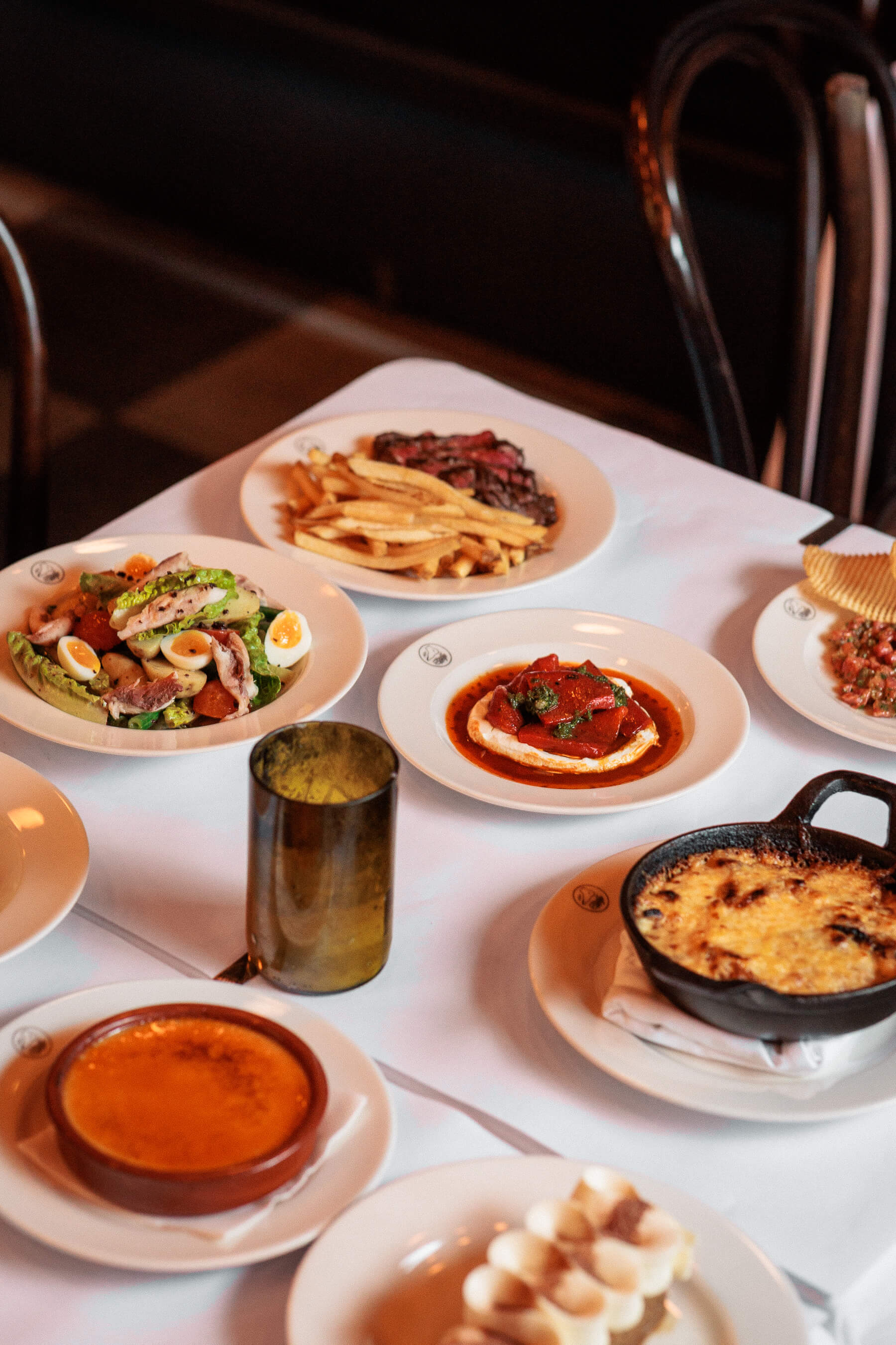 High-angle view of Le Foote dinner table featuring grilled lamb, baked cheese, roasted peppers and plated desserts