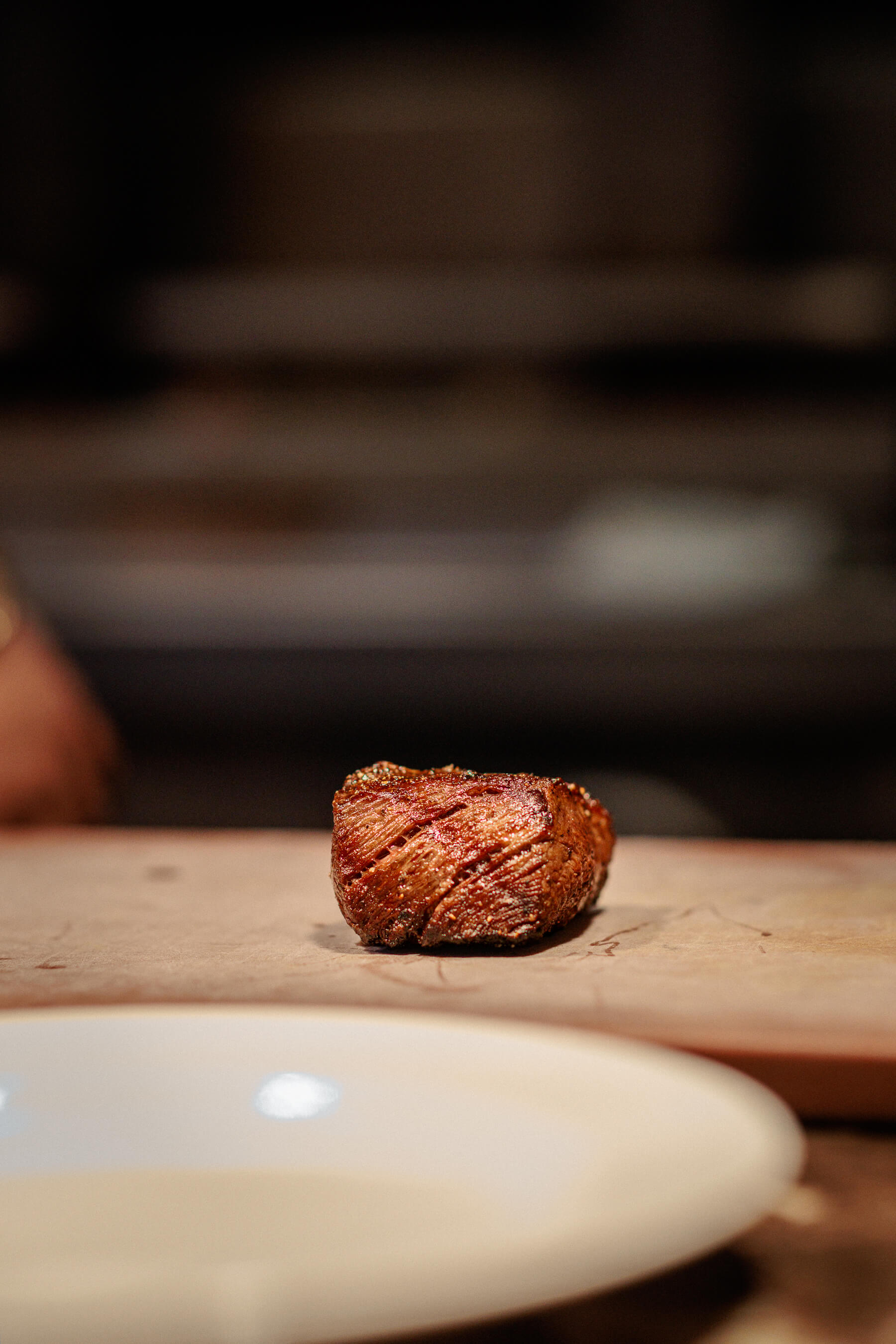 Another view of a seared steak placed on a cutting board, highlighting its caramelized crust and shape before slicing.