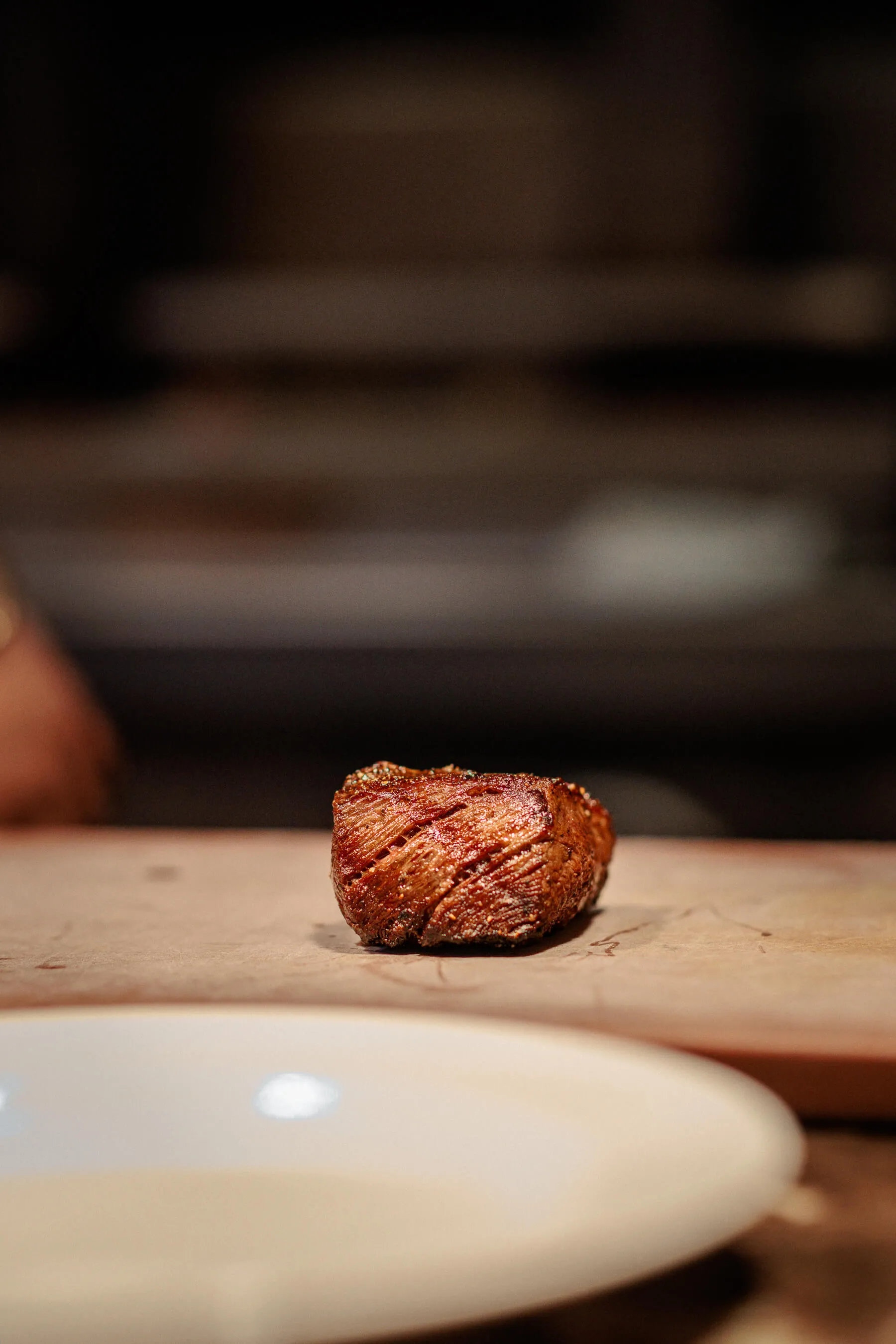 Another view of a seared steak placed on a cutting board, highlighting its caramelized crust and shape before slicing | EDG Studios