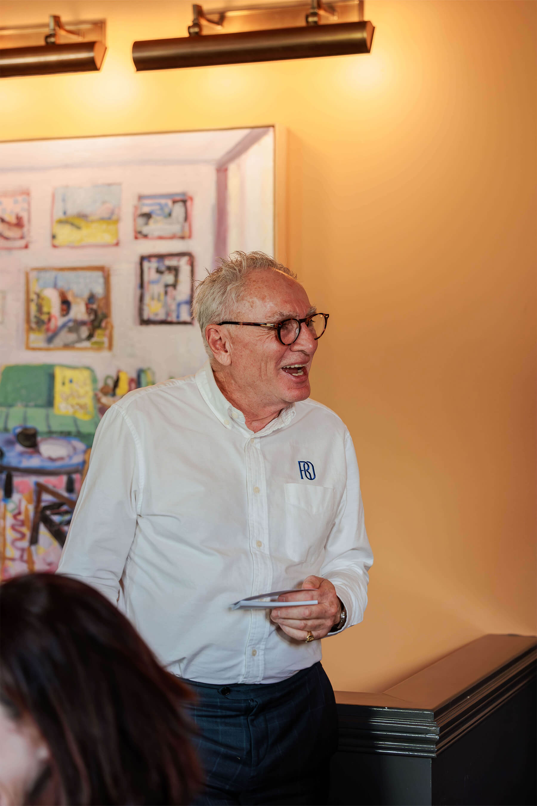 The same senior man from earlier smiling mid-sentence, holding a tablet during his talk at the Royal Oak Floors event at Ursula’s Paddington.
