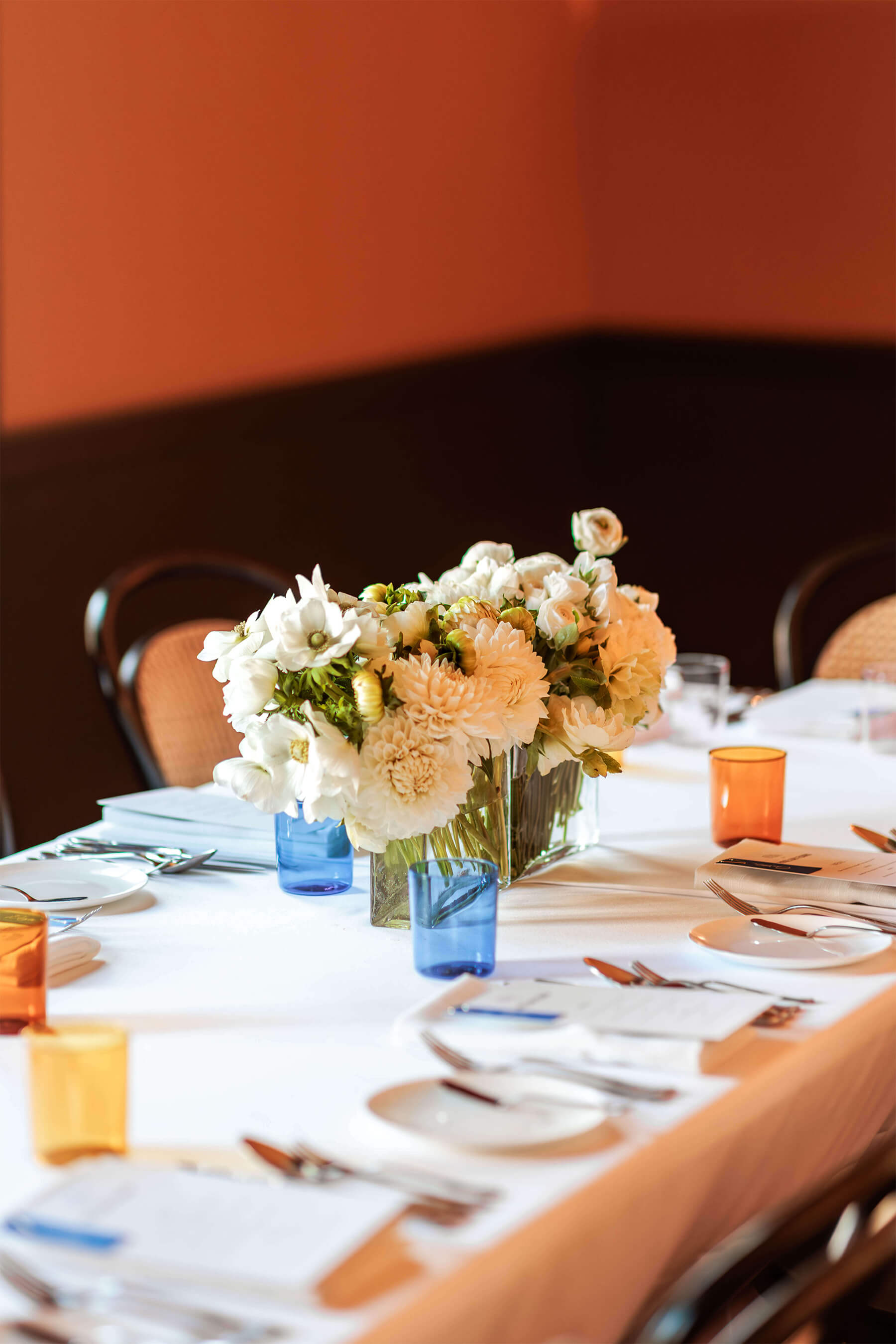Full table setting with florals, blue and amber tumblers, menus, and white napkins, styled for the Royal Oak Floors event.