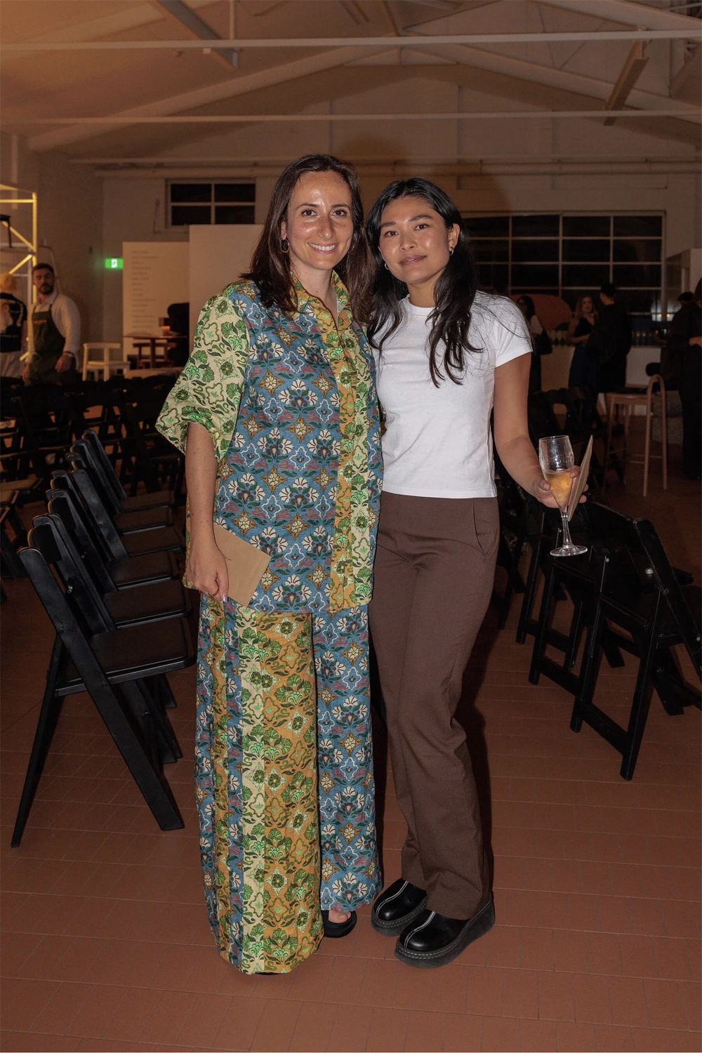 Two attendees standing arm in arm in the event space following the DesignByThem panel discussion.
