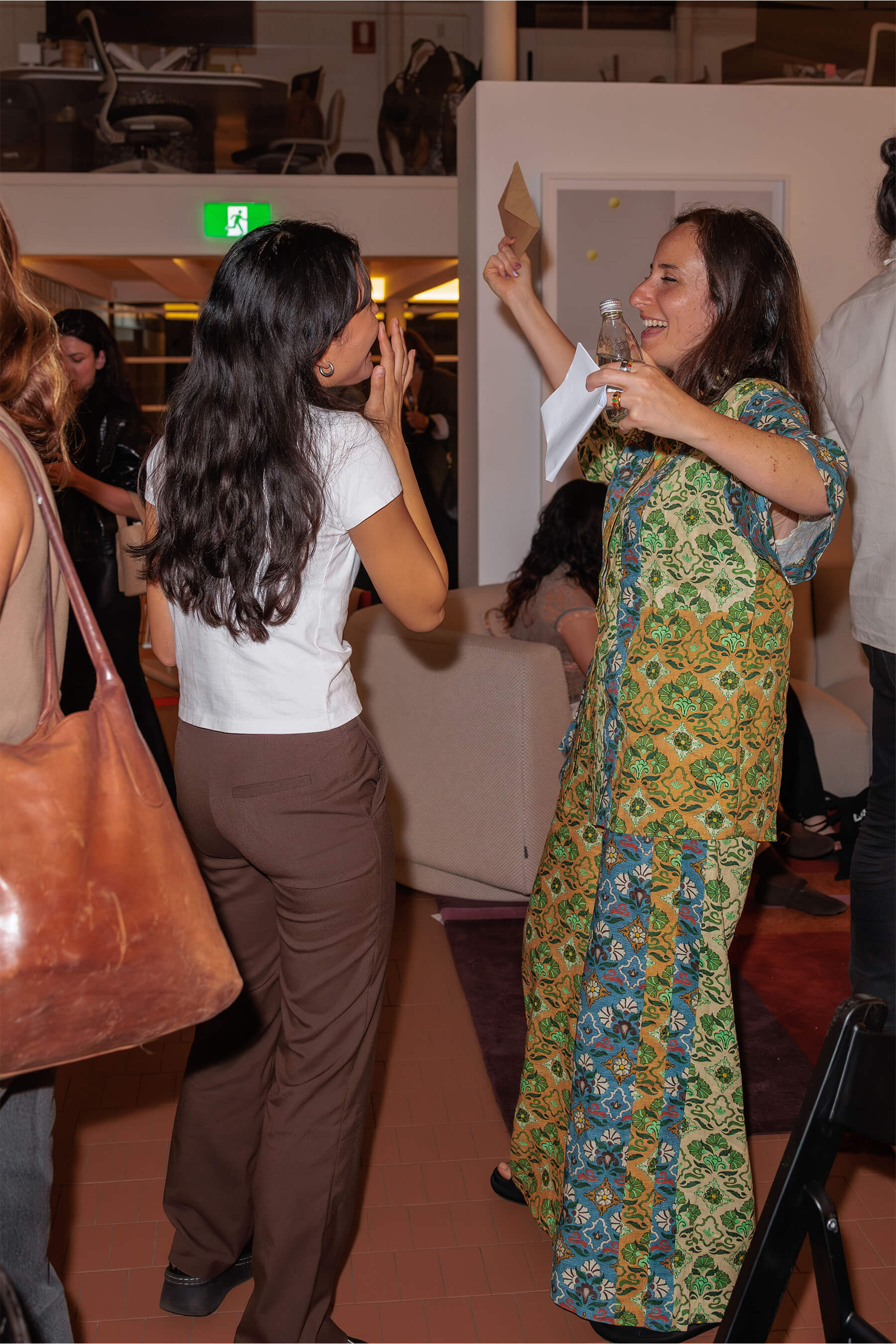 Two attendees animatedly chatting after the panel, surrounded by guests and modern furnishings.