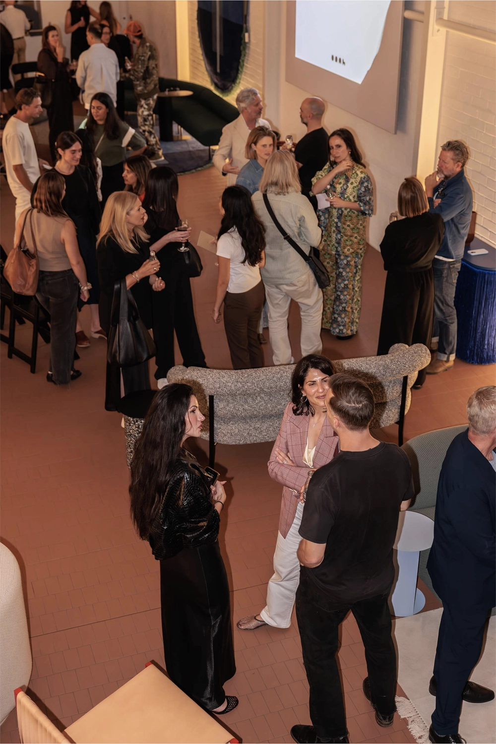 Guests mingle and chat during the post-panel reception at DesignByThem’s “I’ll Be Happy When” event, surrounded by DBT furniture and warm lighting.