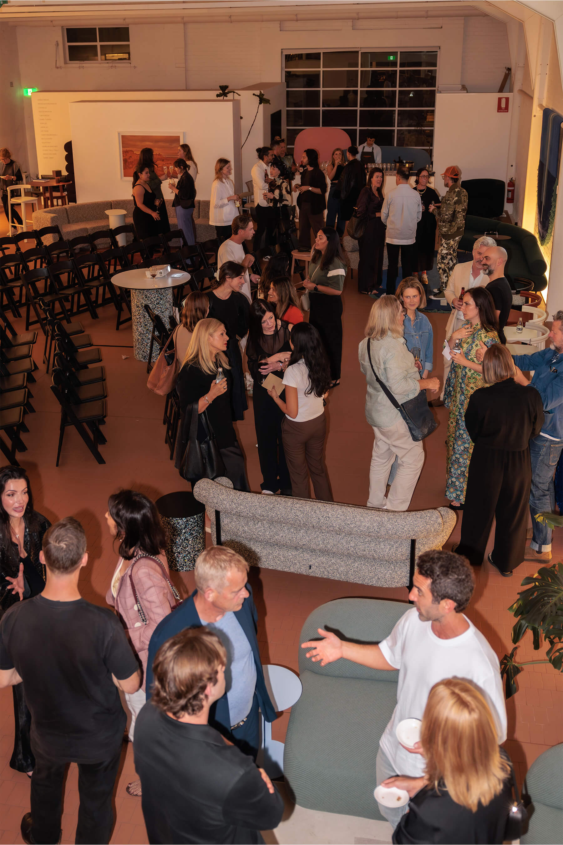 Aerial view of the DesignByThem “I’ll Be Happy When” event with attendees gathered across the showroom space for drinks and conversation after the speaker panel.