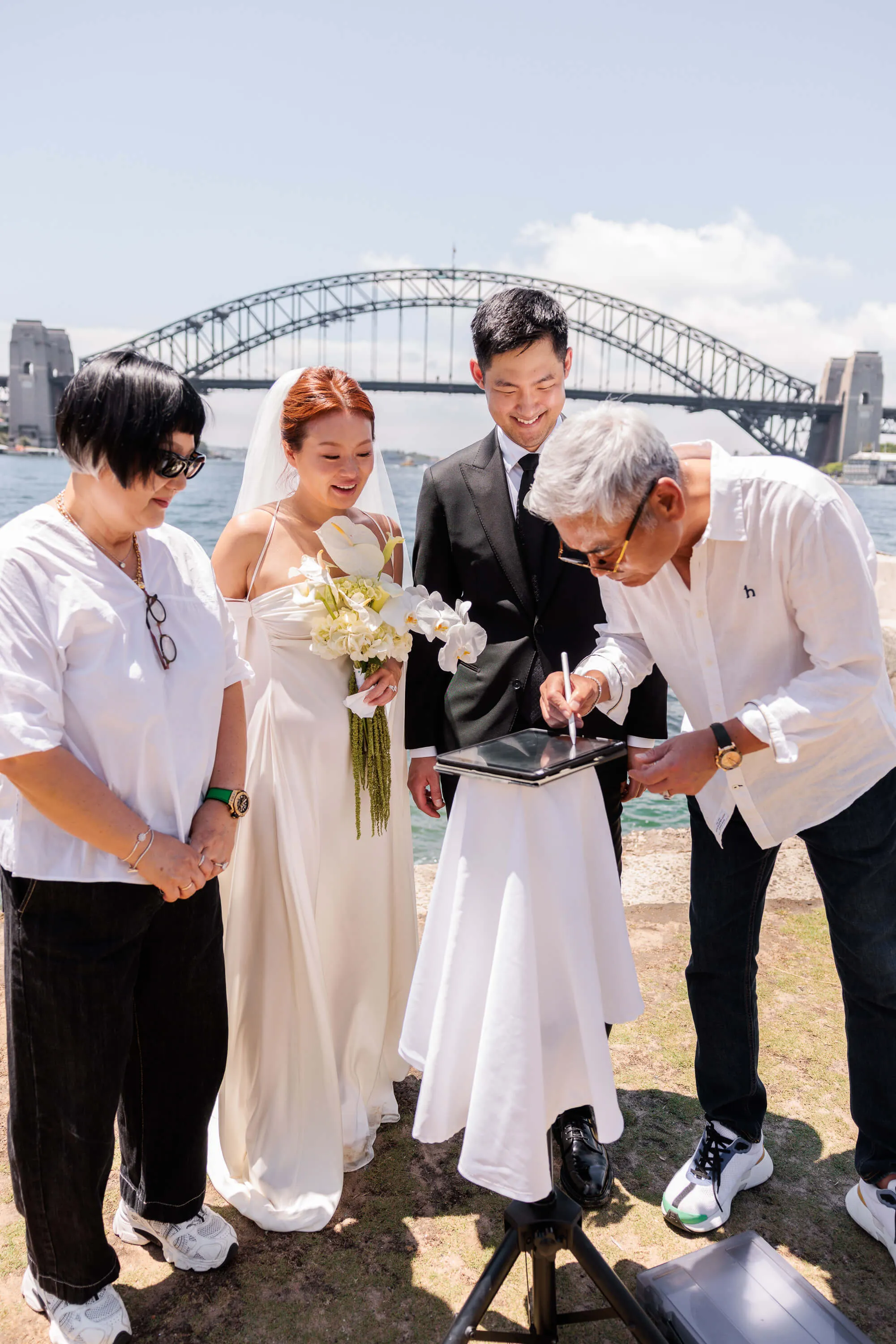 Melanie and Dai smile as the marriage register is signed, surrounded by immediate family and loved ones | EDG Studios