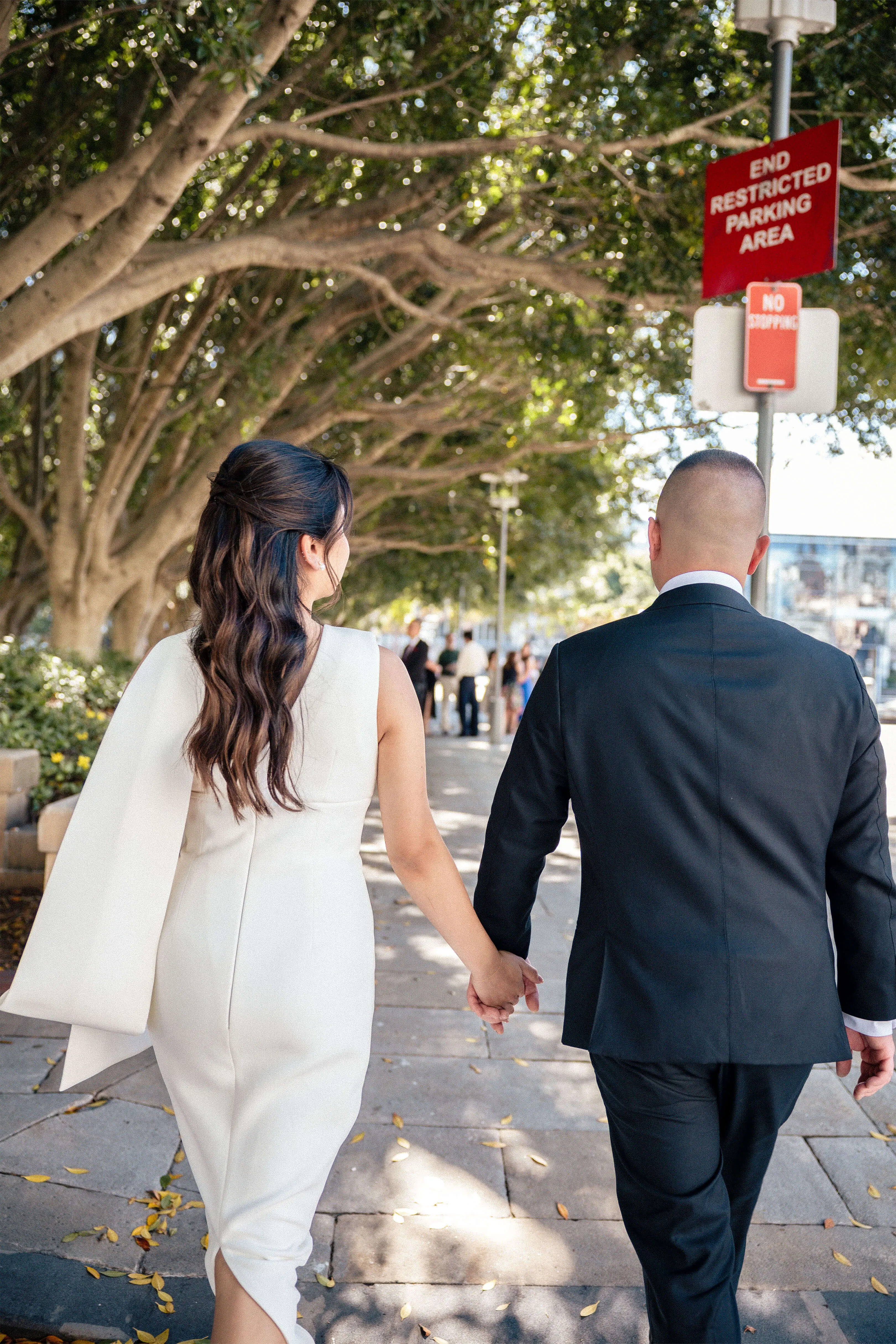 Candid walk through a sun-dappled footpath, brideโs dress flowing as couple walks hand-in-hand | EDG Studios