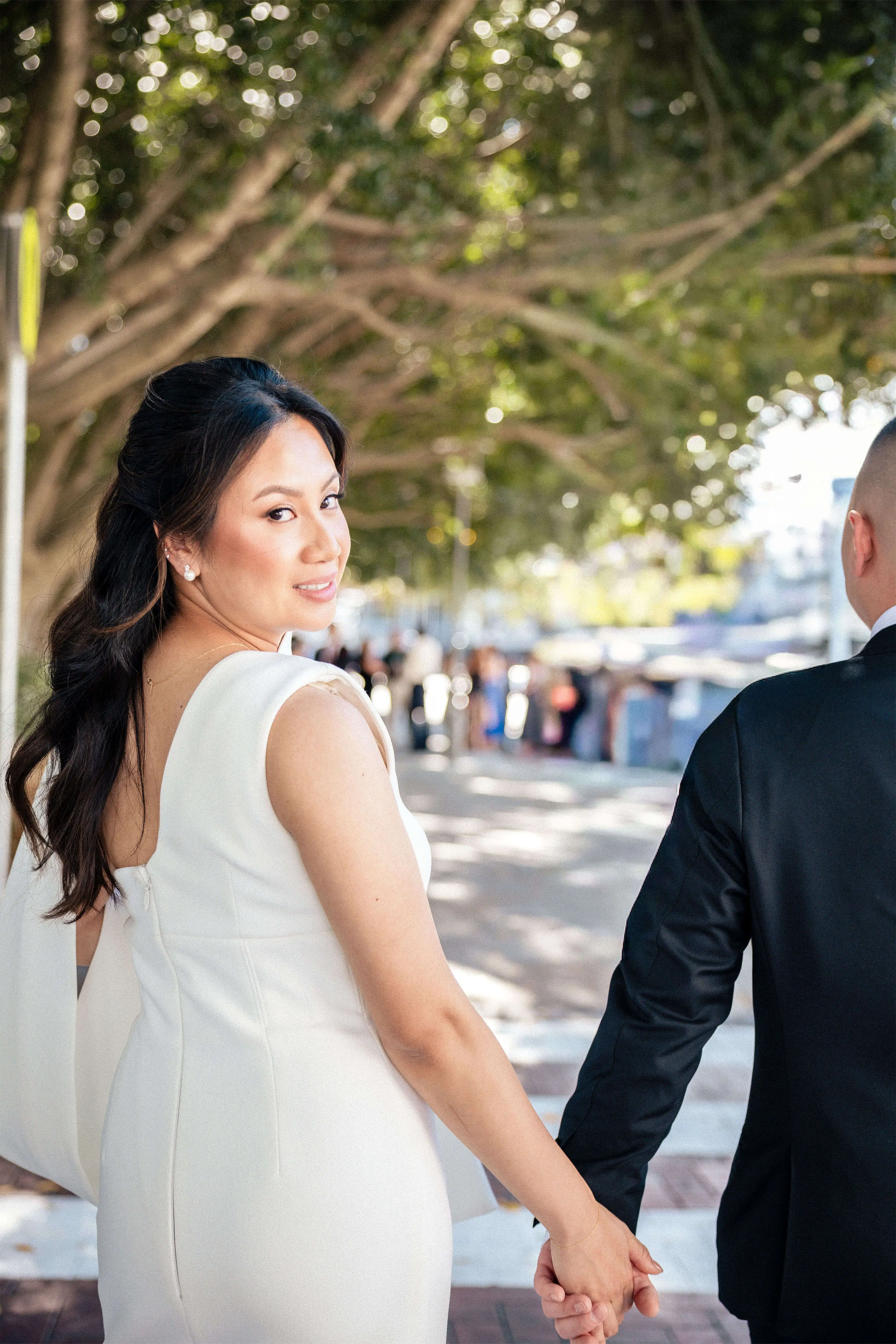 Bride glancing over her shoulder with a soft smile while holding hands with the groom | EDG Studios