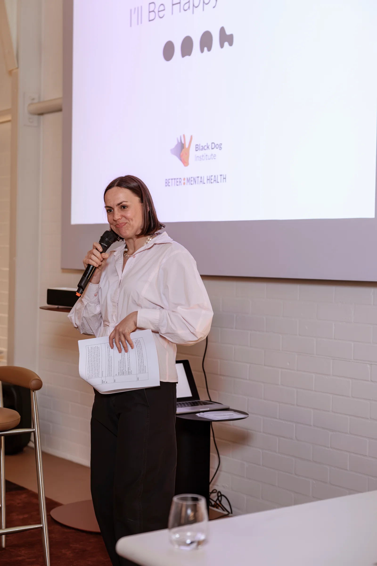 Event host welcoming guests beneath the I'll Be Happy When screen, photographed by EDG Studios.