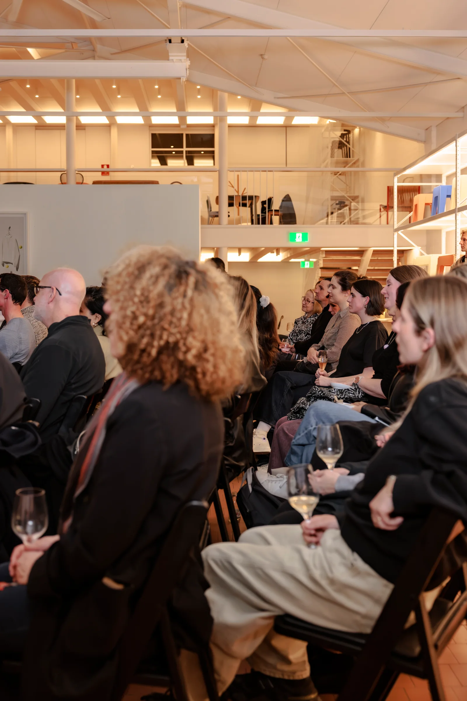 Guests listening to the panel beneath the showroom mezzanine at Design By Them, photographed by EDG Studios.