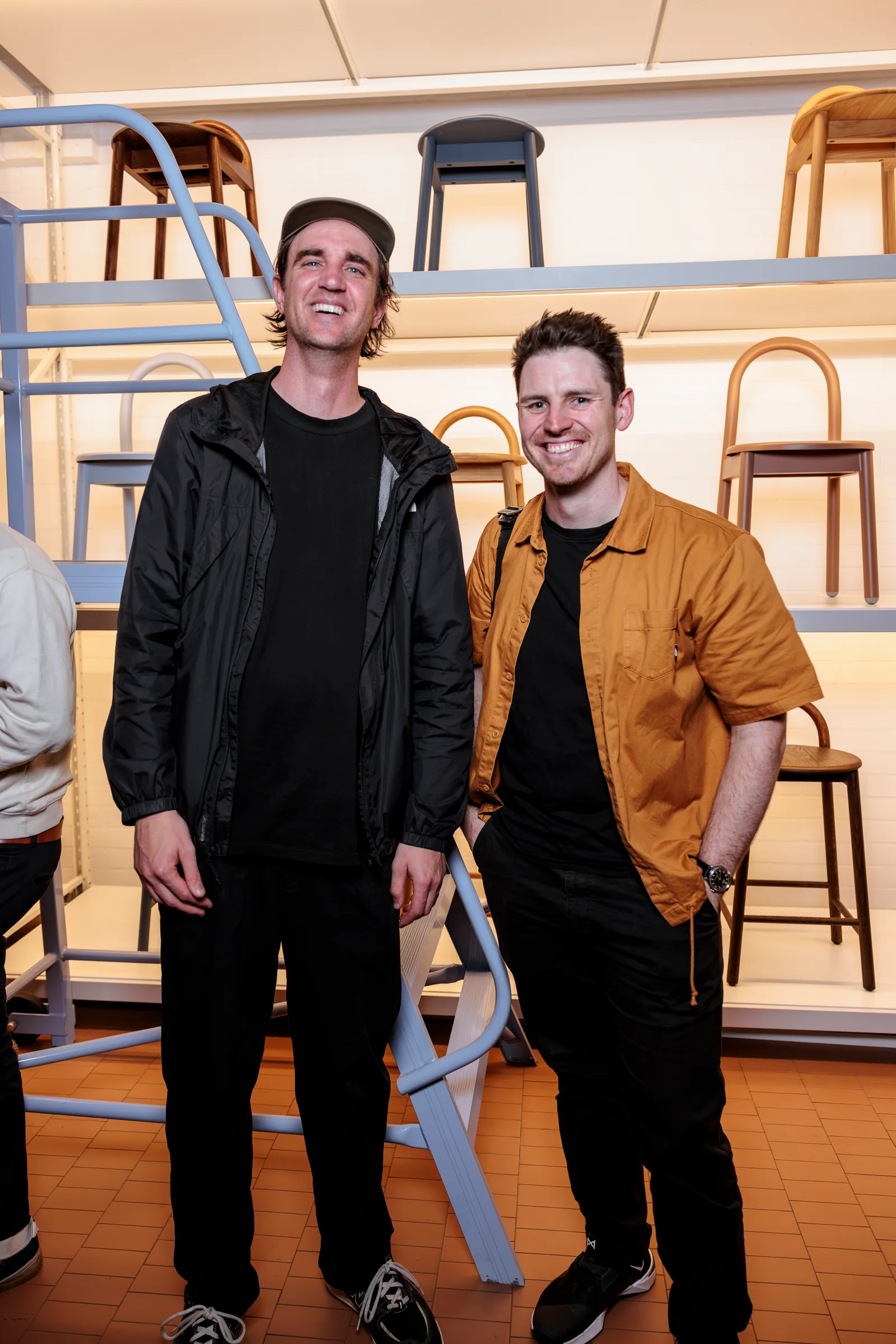 Two attendees posing beside the illuminated stool display at Design By Them, photographed by EDG Studios.