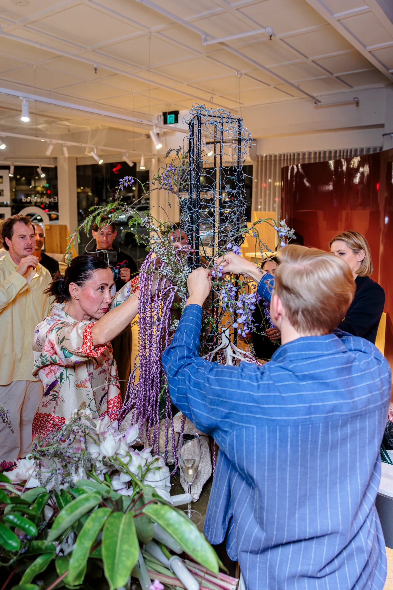 Guests adding stems to a shared floral installation in the showroom, photographed by EDG Studios.