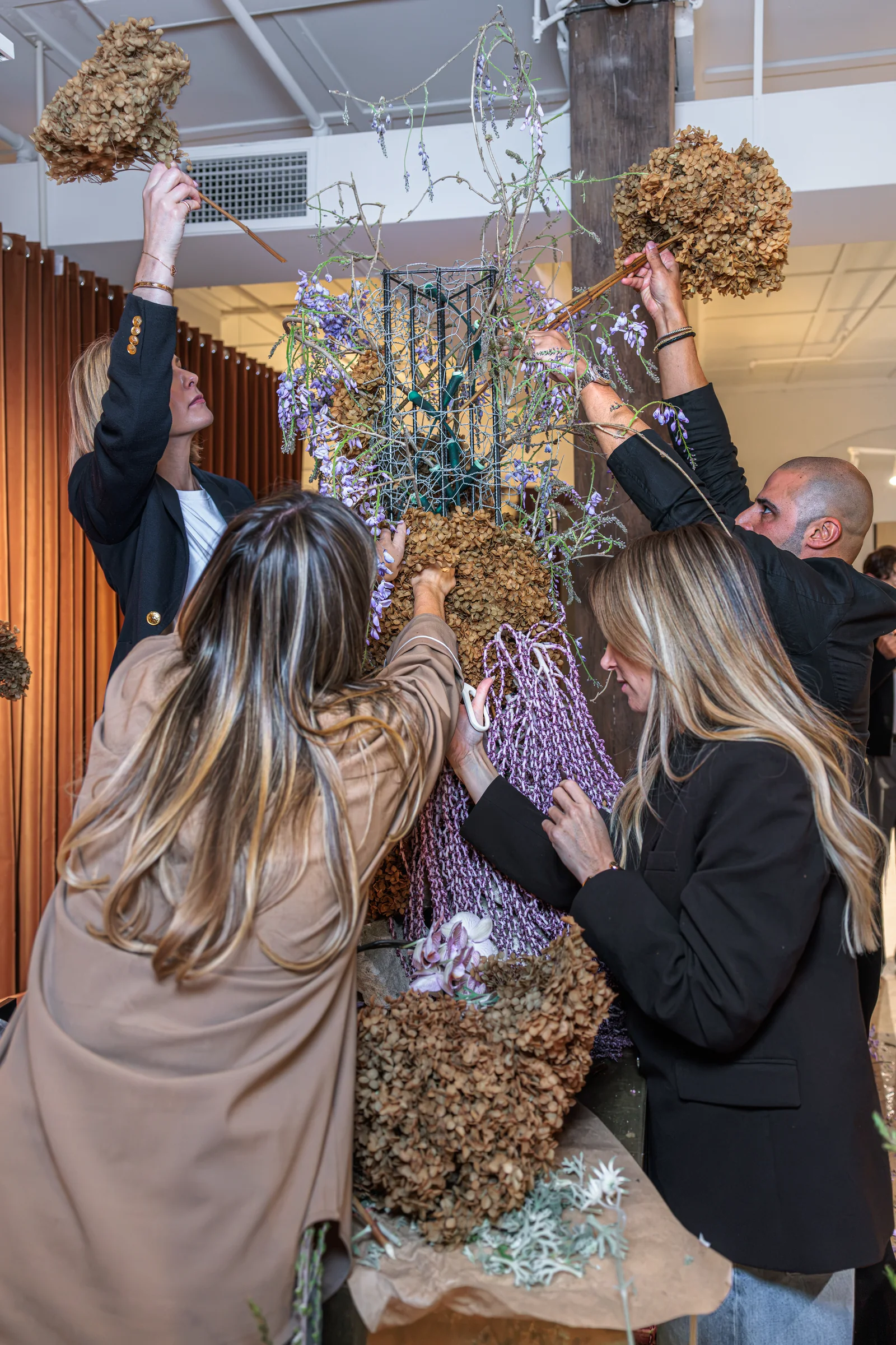 Workshop guests lifting hydrangeas into the shared floral sculpture, photographed by EDG Studios.