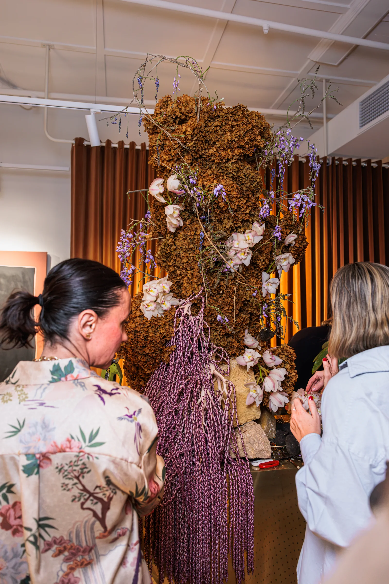 Two guests inspecting flowers on the shared showroom installation, photographed by EDG Studios.