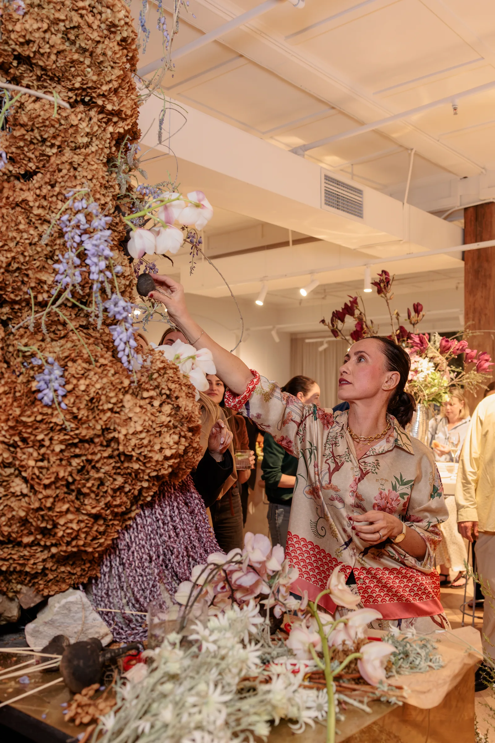 Guest arranging white hydrangeas and foliage in the floral sculpture, photographed by EDG Studios.