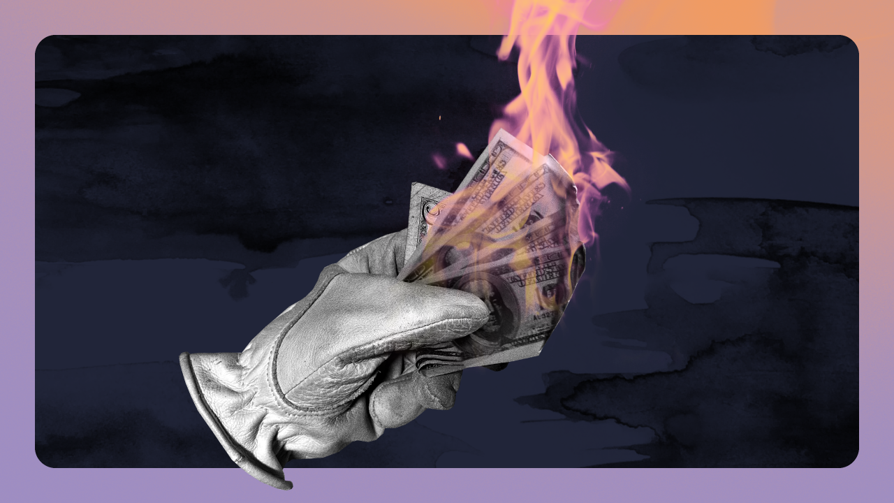 Work glove holding burning stack of money