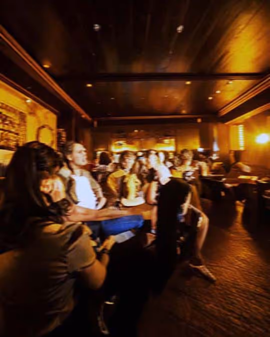 Several people enjoying drinks and conversation in a lively bar.